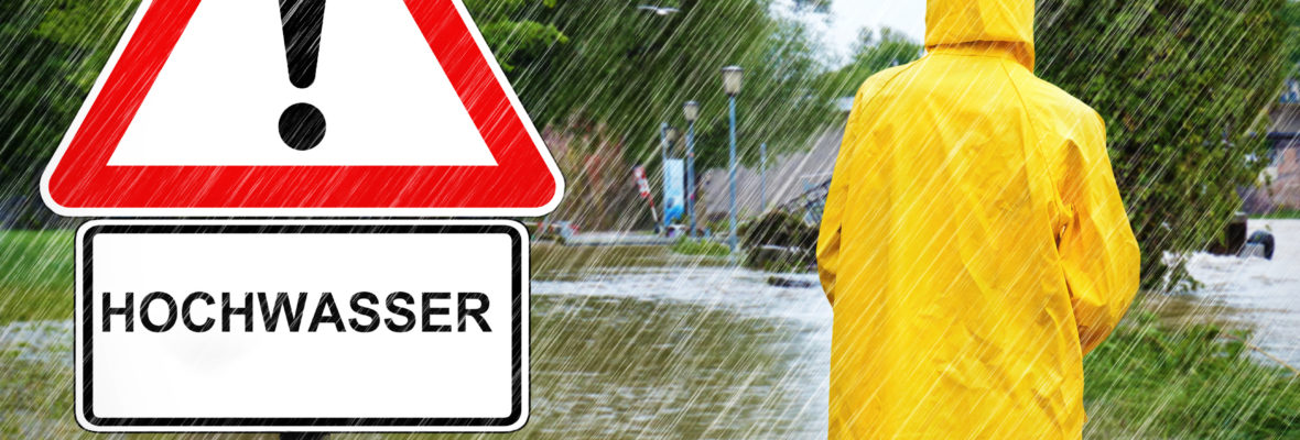 Person vor Schild Achtung Hochwasser