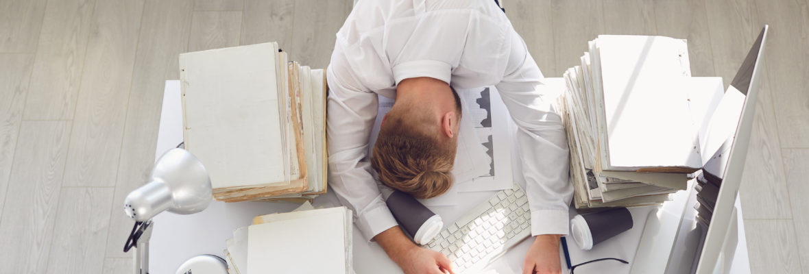 Mann schläft bei Arbeit am Schreibtisch ein