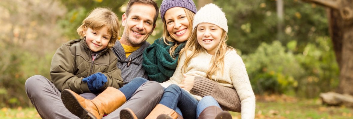 Junge Famile sitz lachend auf Herbstlaub