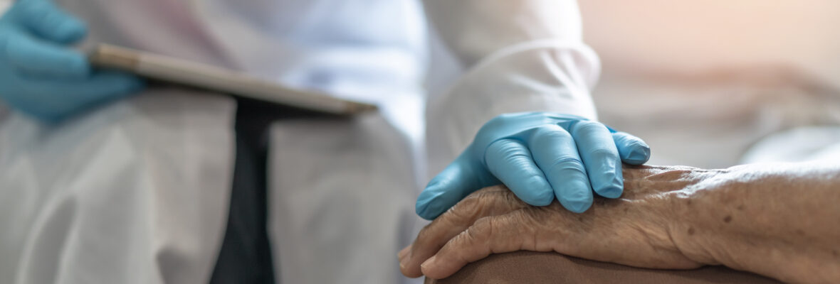 Hand eines Arztes legt sich auf die Hand eines Patienten