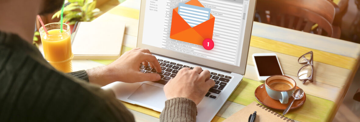 Mann sitzt vor dem Laptop und schreibt eine E-Mail.