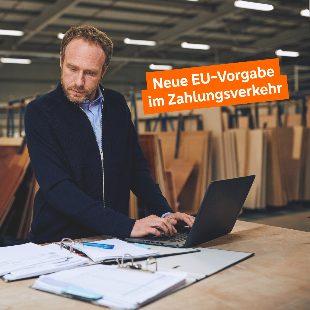 Mittelalter Mann bedient Laptop und schaut dabei auf Geschäftsunterlagen.