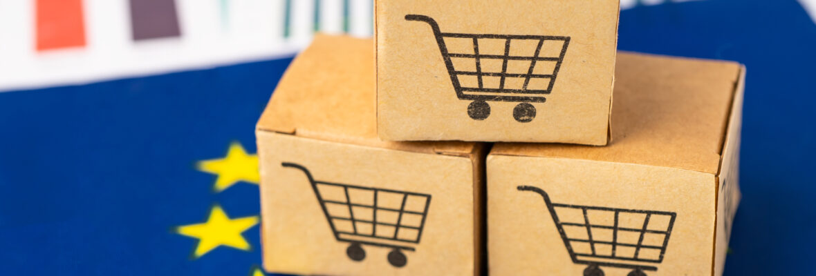 Drei kleine Pakete mit einen Einkaufswagen-Icon liegen auf der Flagge der europäischen Union