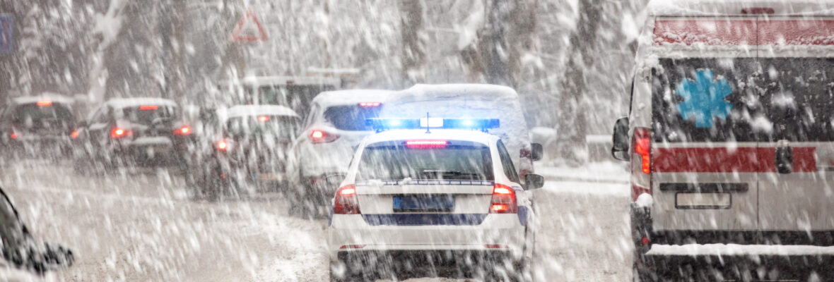 Fahrzeuge auf einer befahrender Straße im Winter. Schnee fällt.