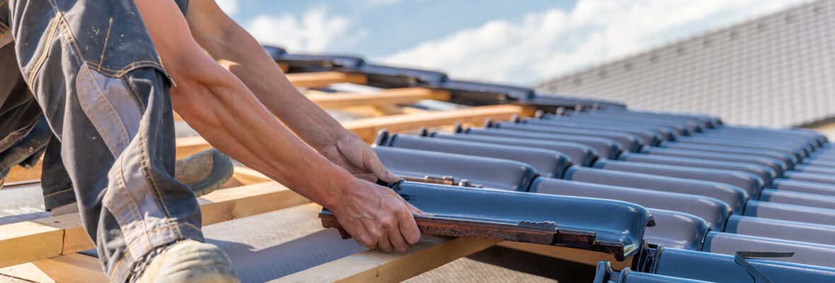 Ein Dachdekcer legt Dachpfannen auf ein neues Dach.