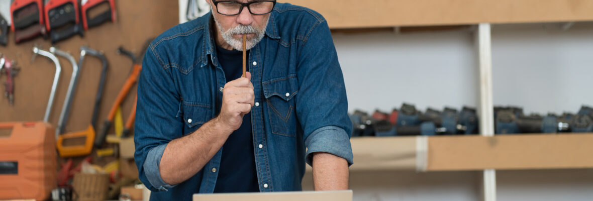 Handwerker schaut mit ernstem Blick auf einen Laptop.
