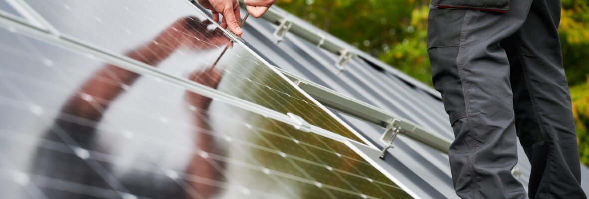 Ein Monteur installiert Photovoltaik-Solarmodule auf einem Hausdach. Nahaufnahme eines Technikers, der mithilfe eines Inbusschlüssels eine Solaranlage montiert. Konzept für alternative, erneuerbare Energien.
