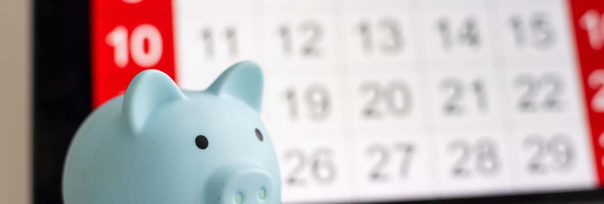 Ein Sparschwein vor einem Kalender
