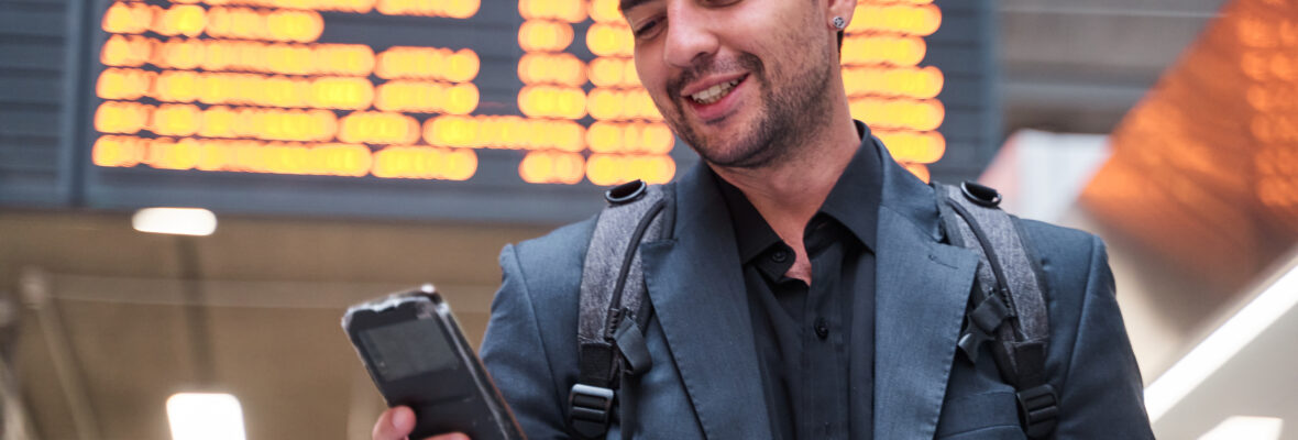 Mann mit Handy in der Hand am Flughafen.